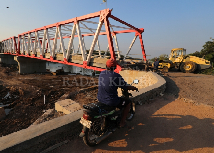 AKSES VITAL: Salah seorang warga sedang mengamati proses pengerjaan Jembatan Jongbiru-Mrican yang direncanakan bakal bisa dioperasikan pada awal Juli nanti.