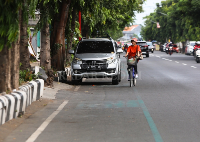 TERGUSUR: Pesepeda di Jl Jaksa Agung Suprapto harus keluar jalur sepeda karena jalur tertutup kendaraan roda empat yang parkir