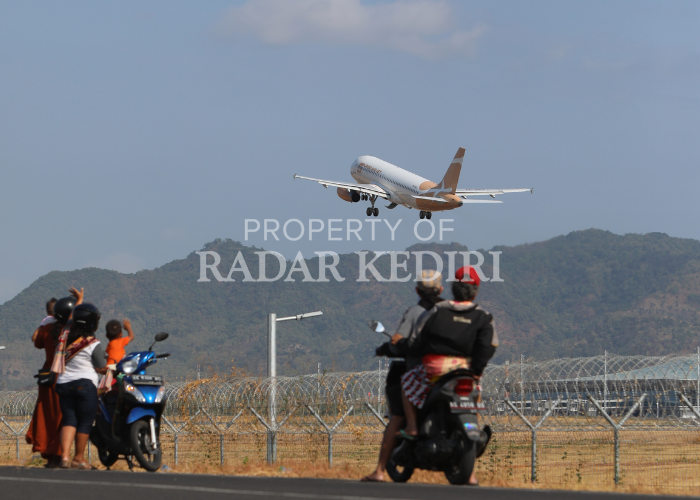 JADI TONTONAN: Warga sekitar bandara menyaksikan pesawat yang baru lepas landas di Bandara Dhoho Kediri, yang dipersiapkan untuk embarkasi haji.