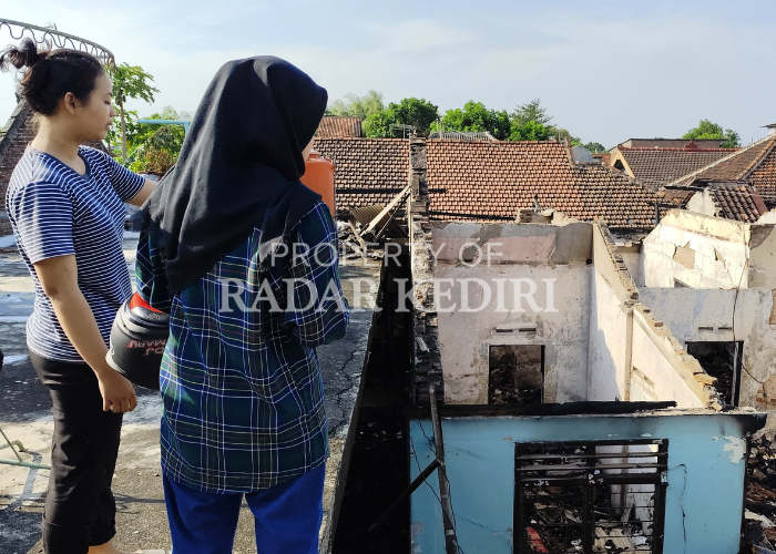LIHAT PUING: Regina (kiri) menyaksikan sisa kebakaran dari lantai dua rumah kosnya.
