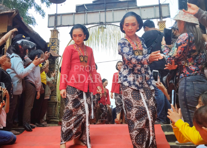 AMBIL GAMBAR: Pengunjung anak anak yang menyaksikan kirab 1 Sura di Petilasan Sri Aji Jayabaya, Desa Menang, Kecamatan Pagu, berusaha mengambil foto gadis yang menjadi peserta pawai kemarin.