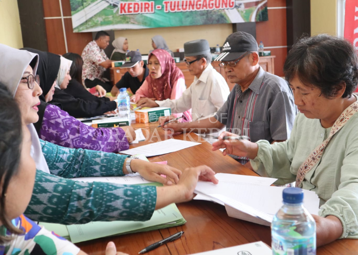 TERIMA UANG: Warga Kelurahan Bujel, Kecamatan Mojoroto, membubuhkan tanda tangan saat acara pemberian uang ganti rugi proyek jalan tol Kediri-Tulungagung di balai kelurahan setempat (18/7).