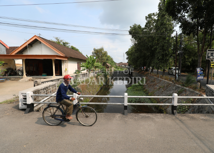 TERCEMAR: Warga melintas di jembatan Sungai Kresek, Kelurahan Tempurejo. Air sungai yang seharusnya bersih kini bercampur dengan sampah plastik.