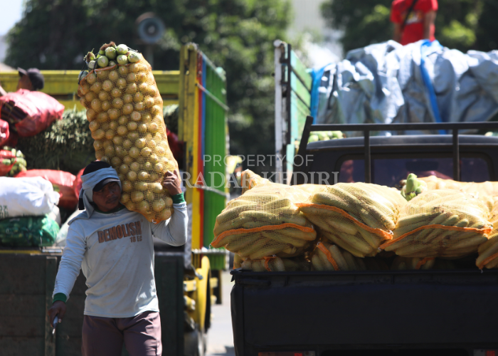 WASPADA DEFLASI: Seorang buruh di Pasar Ngronggo, Kecamatan Kota mengangkut satu karung jagung.