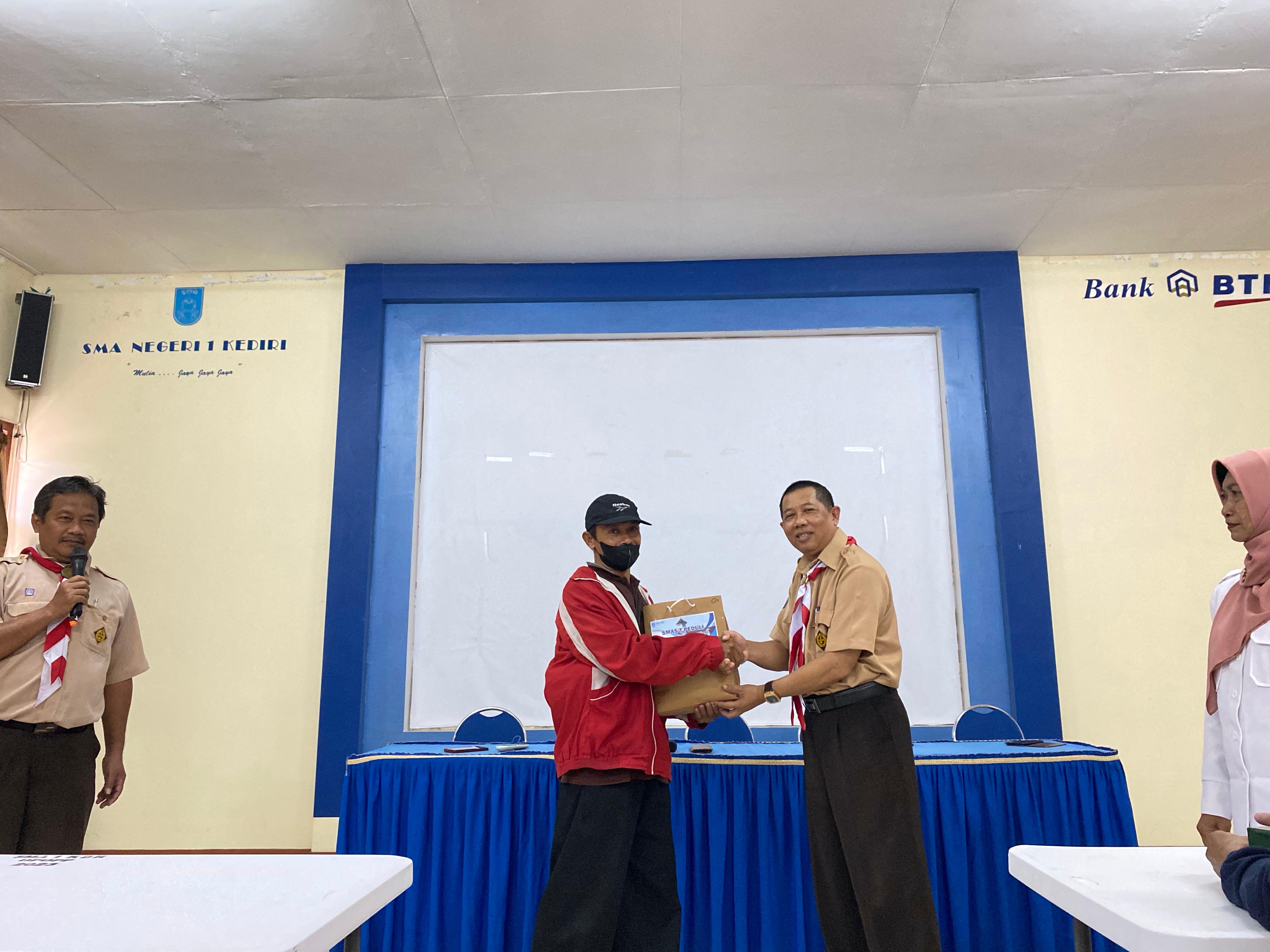 RINGANKAN BEBAN: Kepala SMAN 1 Kediri Widayat serahkan bantuan seragam kepada salah satu walimurid.