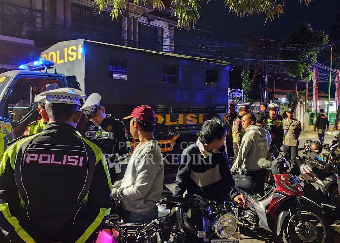 KENA RAZIA: Anggota Polres Kota Kediri memeriksa kendaraan bermotor yang parkir di tepi jalan hingga larut malam.