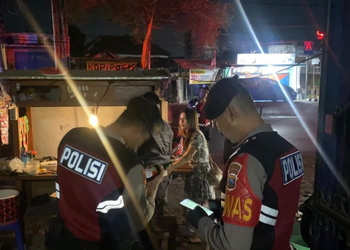 SIKAT MIRAS Dua anggota Polres Kediri Kota mengecek kandungan minuman yang ada di botol saat melakukan patroli malam.