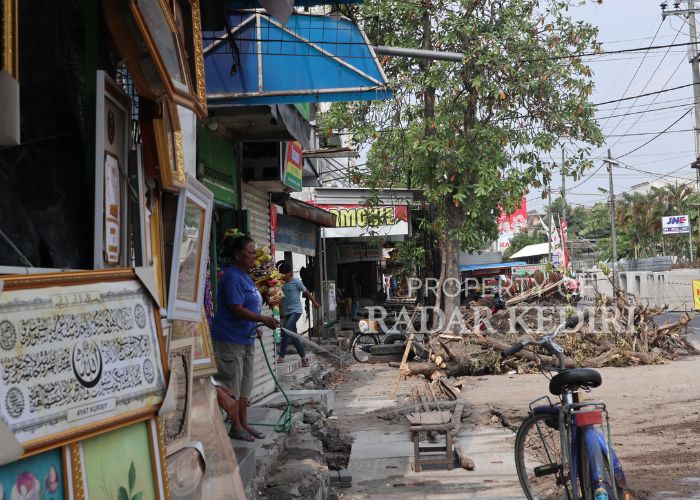 BERSIH-BERSIH: Warga menyiram di halaman depan rumahnya untuk menghindari debu yang berterbangan.