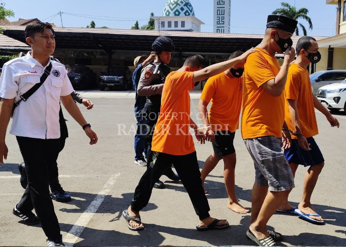 PESAKITAN: Polisi menggelandang tersangka penjual miras es moni (depan, pakai peci) menuju Mapolres Kediri Kota.