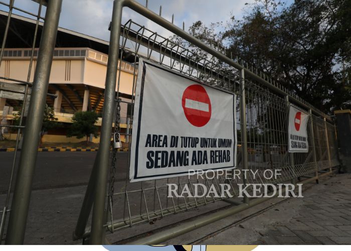 DIPERBAIKI: Ada peringatan berupa banner di pagar GOR Joyoboyo yang pintunya sedikit terbuka.