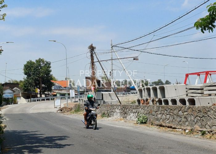 SIAP DIBANGUN Pengendara motor melintas di depan material proyek untuk drainase di Jalan PG Meritjan.