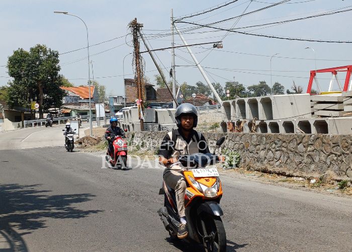 SIAP DIBANGUN Pengendara sepeda motor melintas di depan material proyek drainase di Jalan PG Meritjan.