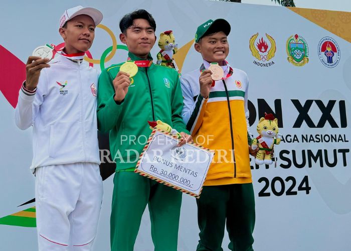 MEMBANGGAKAN Muhammad Andy Royan (tengah) menunjukkan medali emas yang diraihnya dari cabang olahraga balap sepeda PON XXI Aceh Sumatera Utara.
