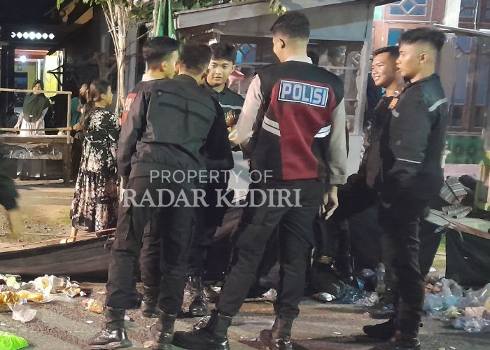PANTAU LOKASI: Anggota polisi mengamankan tempat kejadian perkara keracunan massal di Desa Krecek, Kecamatan Badas.