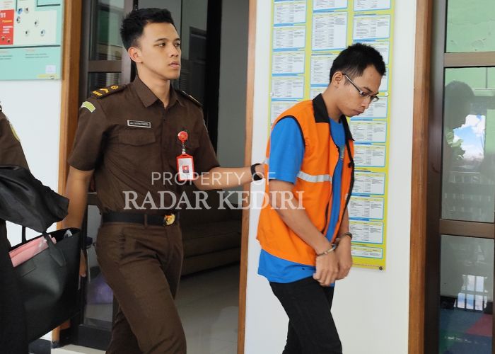 MENUNDUK: Terdakwa Fikri dikawal petugas kejaksaan usai menjalani sidang di Pengadilan Negeri Kota Kediri.