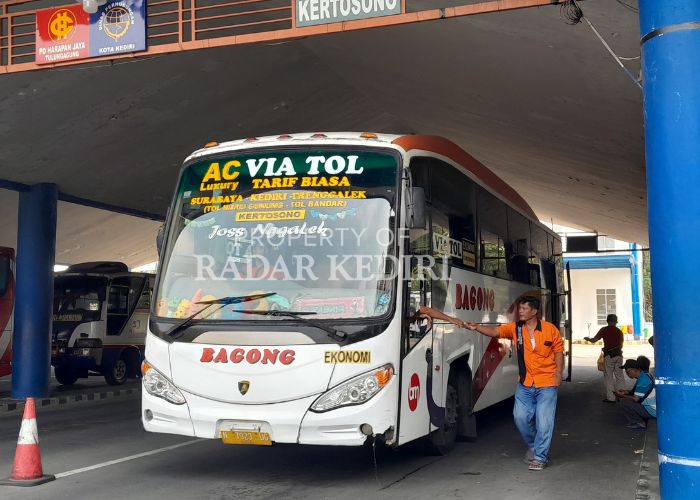 TUNGGU PENUMPANG: Seorang kernet beridiri di bus ekonomi AKDP di Terminal Tamanan Tipe A Kota Kediri.