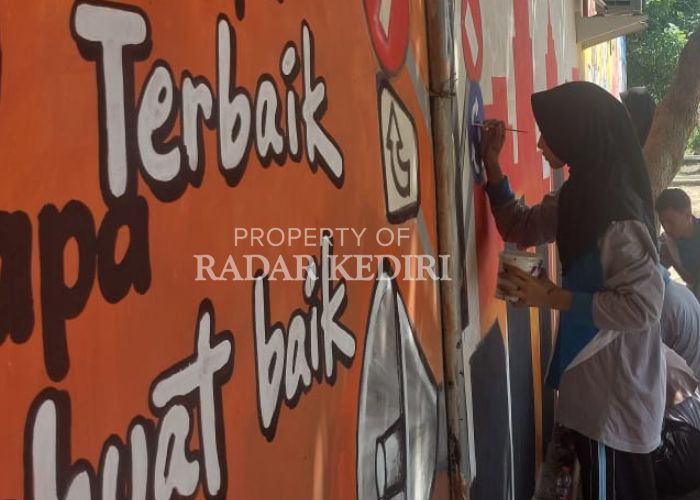 KONSENTRASI: Seorang pelajar saat menggoreskan kuasnya ke tembok yang ada di Polsek Plemahan.