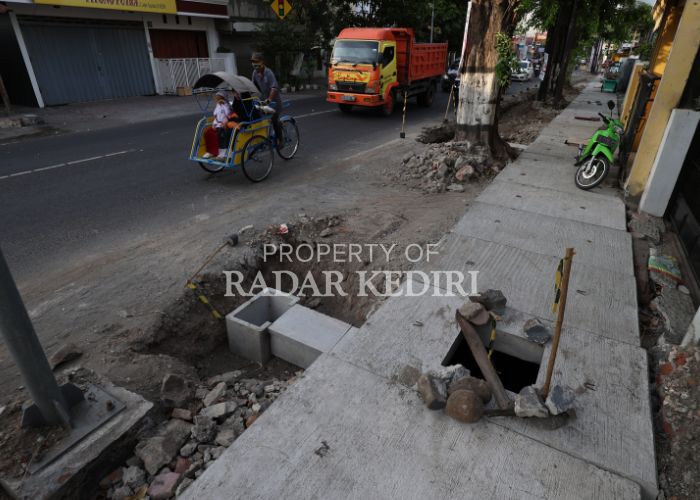 TETAP LANJUT: Pengendara becak melintas di depan proyek drainase yang berada di Jalan Letjen Suprapto,