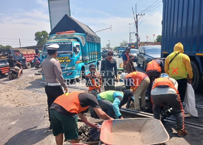 TERSENDAT: Pekerja proyek memperbaiki bantalan rel Kereta Api (KA) di Simpang Mengkreng Kediri. Kegiatan tersebut berimbas pada tersendatnya arus lalu lintas.