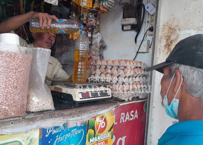 INFLASI LAGI: Seorang pedagang menuangkan migor ke dalam botol.
