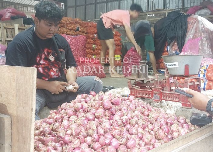 MELAMBUNG: Penjual bawang merah di Pasar Induk Pare melayani pembeli.