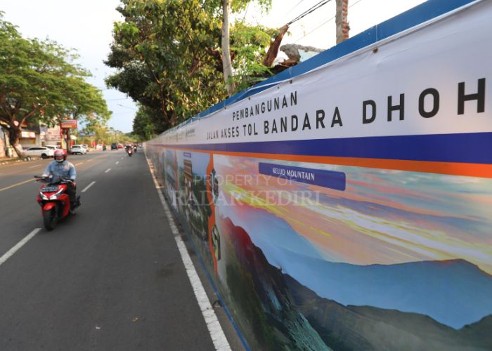 Banner tentang informasi proyek tol akses ke Bandara Dhoho terpasang di pagar pembatas proyek titik nol tol di Jl Mayjen Sungkono,Kelurahan Semampir,Kota Kedir