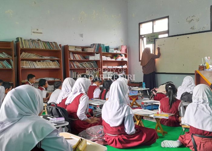 Puluhan siswa kelas V SDN Pare 5 belajar lesehan di ruang perpustakaan karena kelas mereka rusak tertimpa pohon beringin pada Selasa (29/10) lalu.