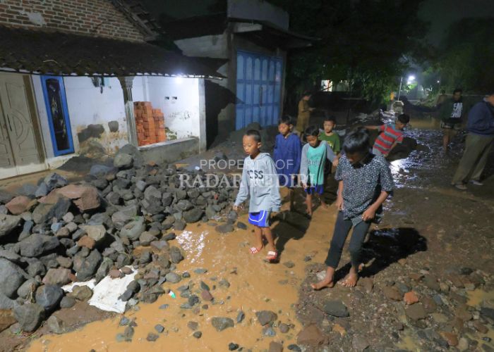 Anak-anak bermain di lingkungan mereka yang berlumpur akibat setelah air bah datang,Minggu (24/11)malam lalu.