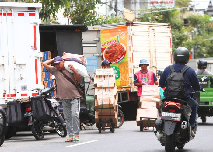 TUNGGU KENAIKAN UMK: Sejumlah pekerja di pusat pertokoan Jl Dhoho melakukan aktivitas bongkar muat kemarin (02/12). Para pekerja berharap mendapat upah sesuai nilai UMK terbaru.