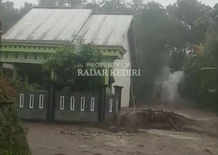 BANJIR: Air dari areal persawahan meluber ke jalan raya di Desa Sepawon, Plosoklaten. Kejadian itu menyebabkan listrik padam karena ada tiang yang ambrol.