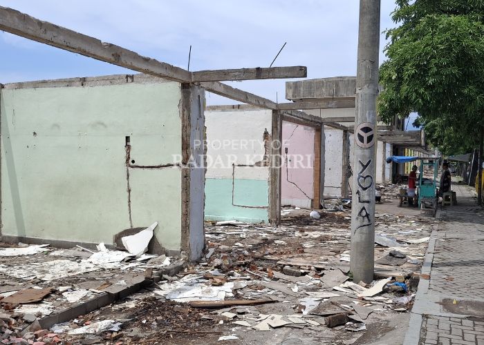 KEBUT: Seorang pedagang kaki lima membuka lapak di depan ruko yang saat ini sedang proses pembongkaran.