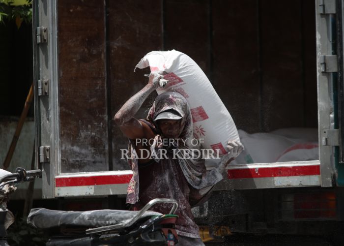 KERJA KERAS: Seorang buruh angkut menurunkan tepung dari truk. Mereka berharap pemberi kerja memberikan upah setara dengan UMK 2025.