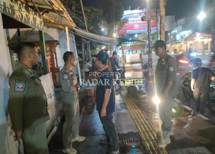 TERTIB: Satpol PP menegur pedagang kaki lima yang nekat berjualan di atas trotoar.