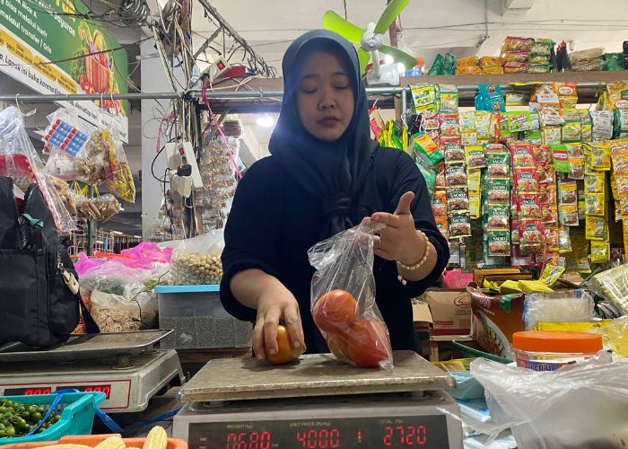 MELONJAK: Penjual tomat di Pasar Setonobetek membungkus tomat.
