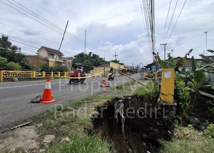 BERBAHAYA: Pengendara motor melintas di tepi plengsengan sungai Gedangsewu yang ambrol.