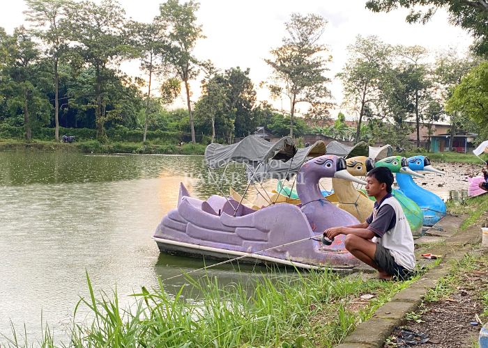 OMZET TURUN Seorang pengunjung sedang memancing di area Bendungan Waru Turi, Desa Gampeng, Kecamatan Gampengrejo kemarin. Pedagang mengeluhkan sepinya pembeli.