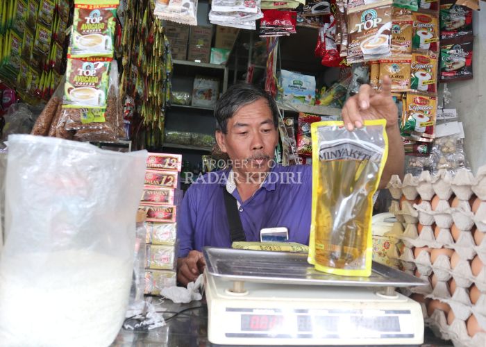 LAMPAUI HET: Pedagang kelontong di Pasar Setonobetek sedang menimbang Minyakita di lapak miliknya. Saat ini minyak goreng sudah melampaui harga eceran tertinggi, untuk merek Minyakita sudah tembus