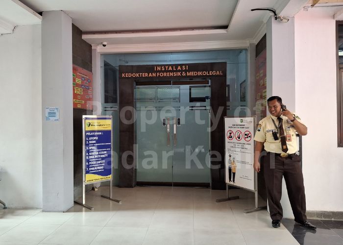 RUANG OTOPSI RS Bhayangkara: Seorang petugas rumah sakit berjaga di depan pintu Instalasi  Kedokteran Forensik dan Medikolegal.