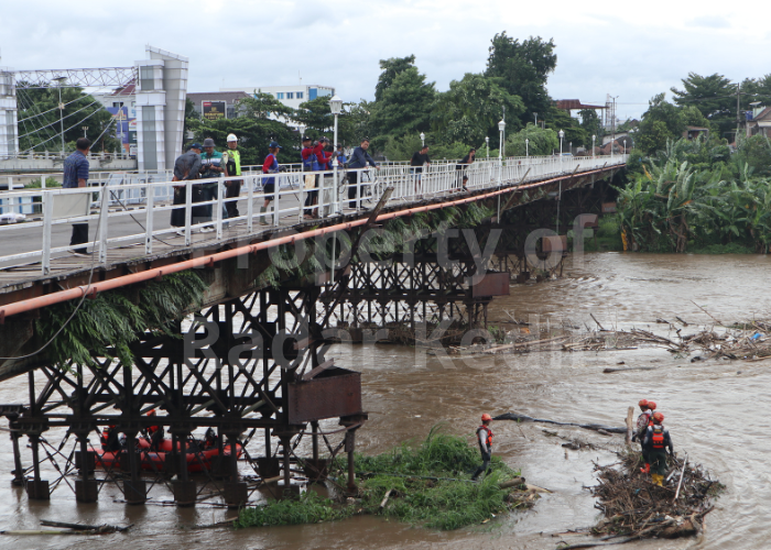 CAGAR BUDAYA: Tim BPBD membersihkan material sampah yang tersangkut di pondasi Jembatan Lama Kediri.