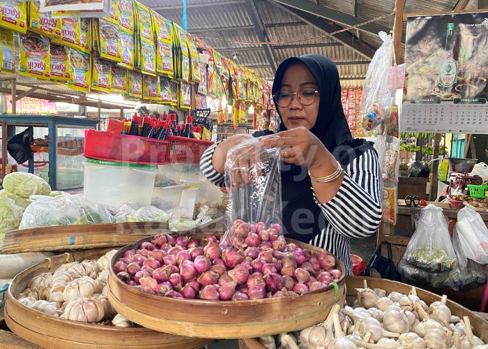 HARGA NAIK: Pedagang pasar memasukan bawang merah ke dalam plastik.