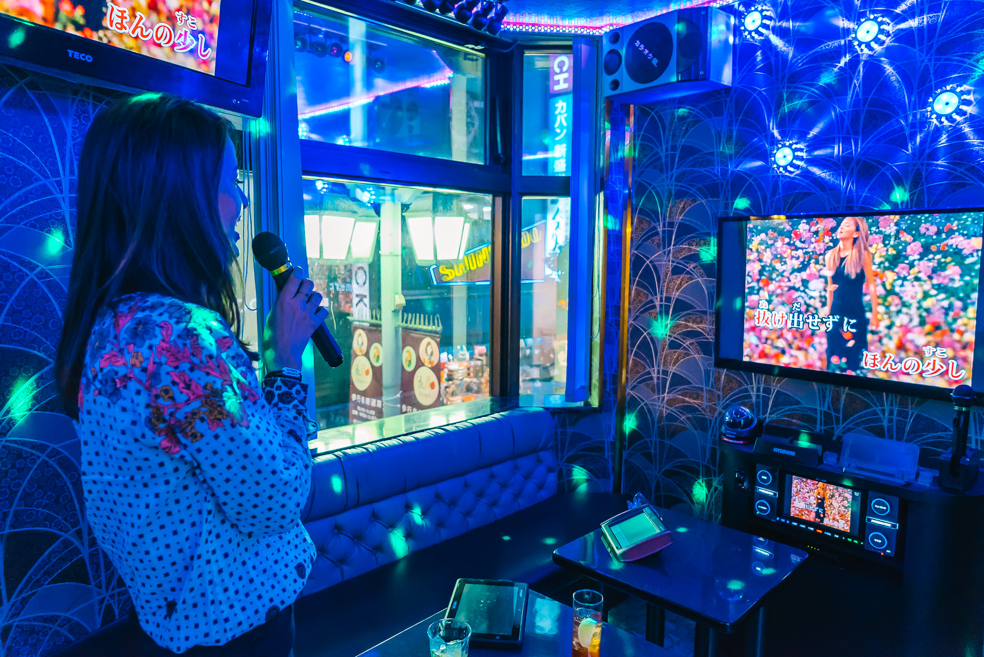 Seorang gadis di Jepang sedang menyanyikan di ruangan karaoke.