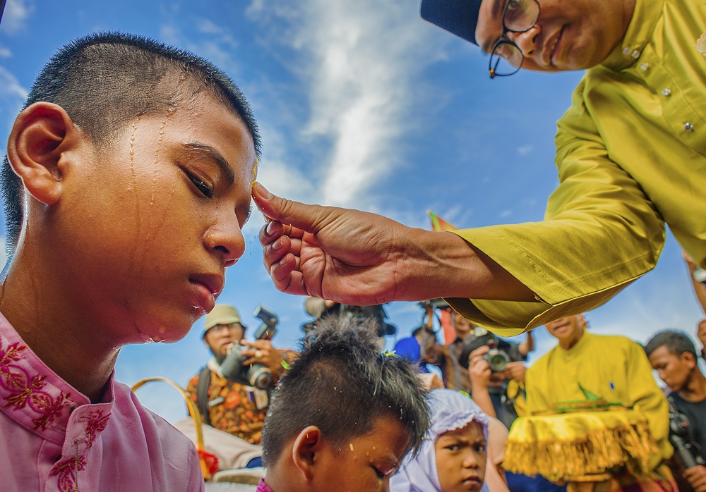 potret anak sedang di basuh air jeruk sebagai bagian dari balimau