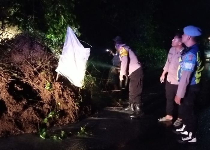 WASPADA: Polisi memberi tanda longsor bagi pengendara yang melintas di Jalan Desa Kalipang.