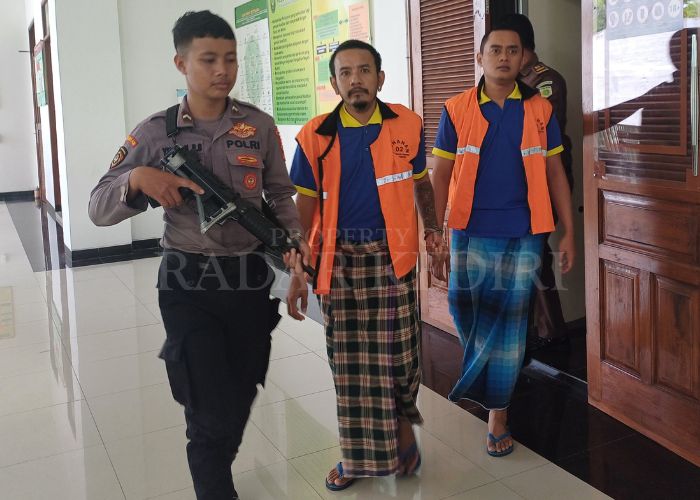 JALANI PERSIDANGAN: Dua terdakwa penghadang Kajari Pradhana dikawal polisi bersenjata usai menjalani persidangan.