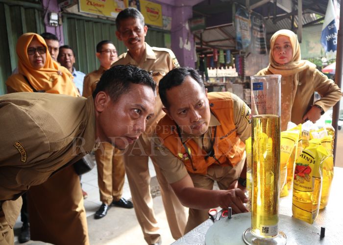 SIDAK: Petugas dari dinas perdagangan saat mengecek takaran Minyakita di Pasar Tradisional Kota Kediri.