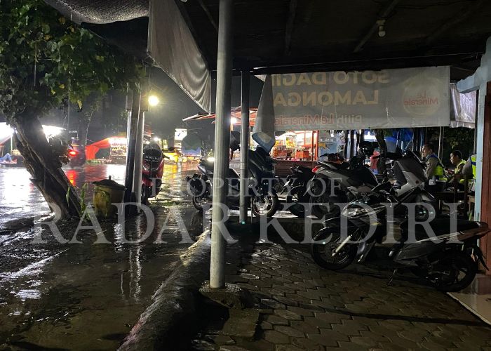 GAGAL OPERASI: Anggota Polresta berada di sekitar GOR Joyabaya. Mereka berteduh saat hujan turun.