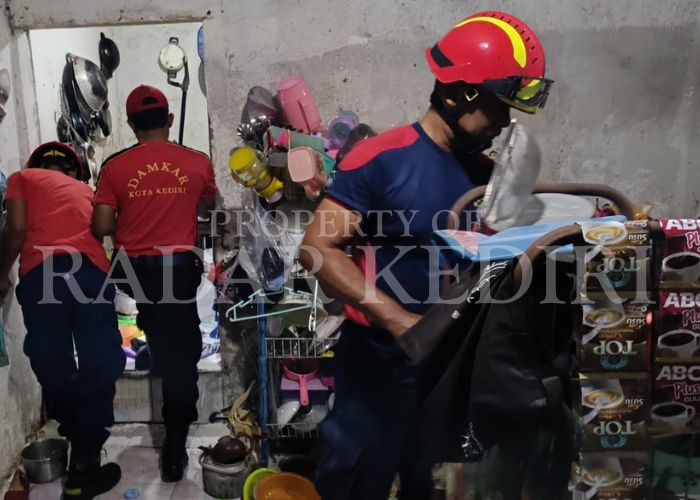 BIKIN HEBOH: Anggota Damkar Kota Kediri sedang mencari ular di dapur rumah warga Kelurahan Dermo.