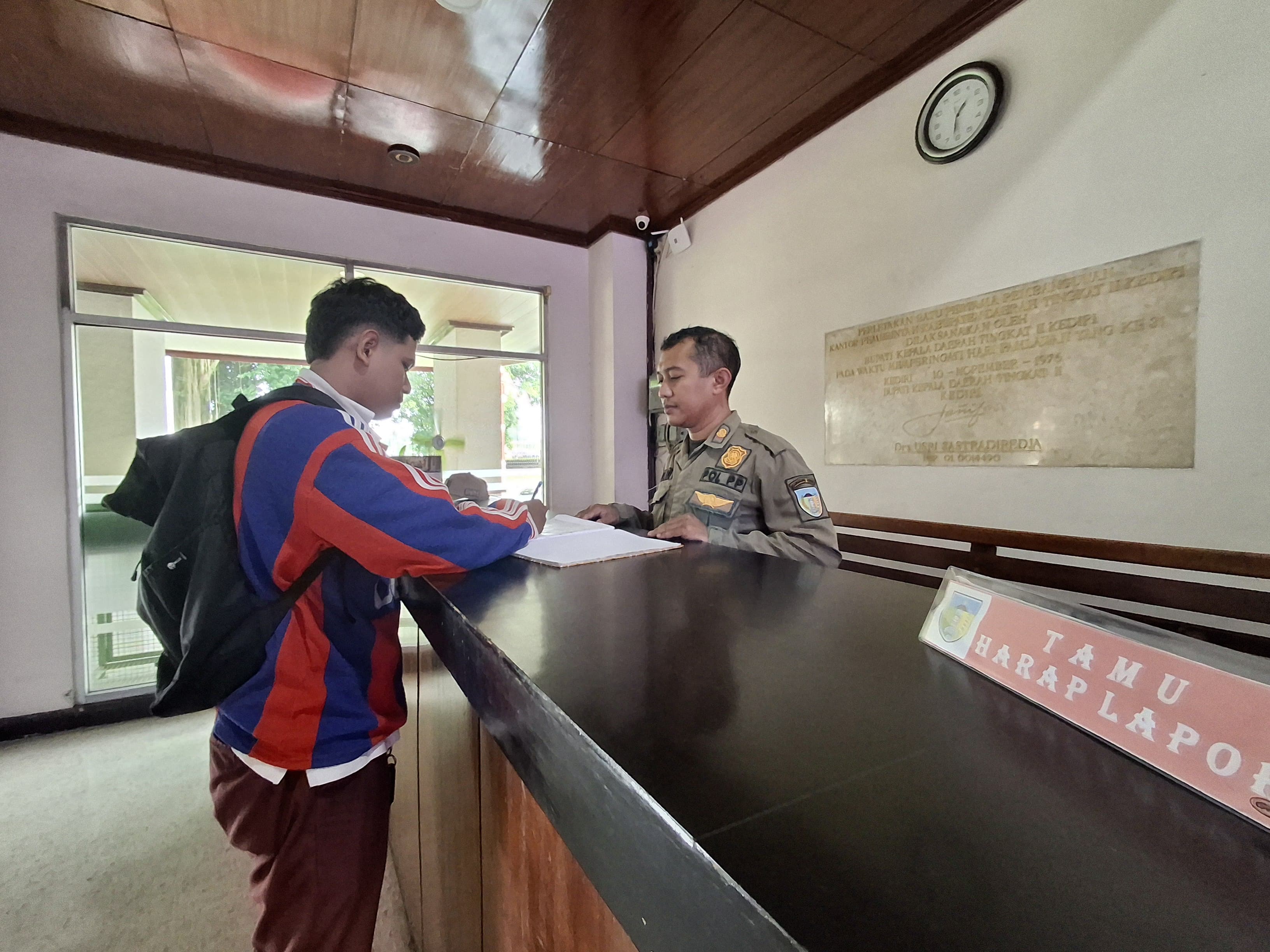 Petugas satpol PP mendata pengunjung kantor Pemkab Kediri. Jika pegawai lain bisa WFH, personel satpol harus tetap bekerja di kantor.