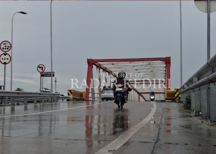 WASPADA CUACA EKSTREM: Pengendara bermotor saat melewati jembatan Jongbiru yang menghubungkan Kota dan Kabupaten Kediri.