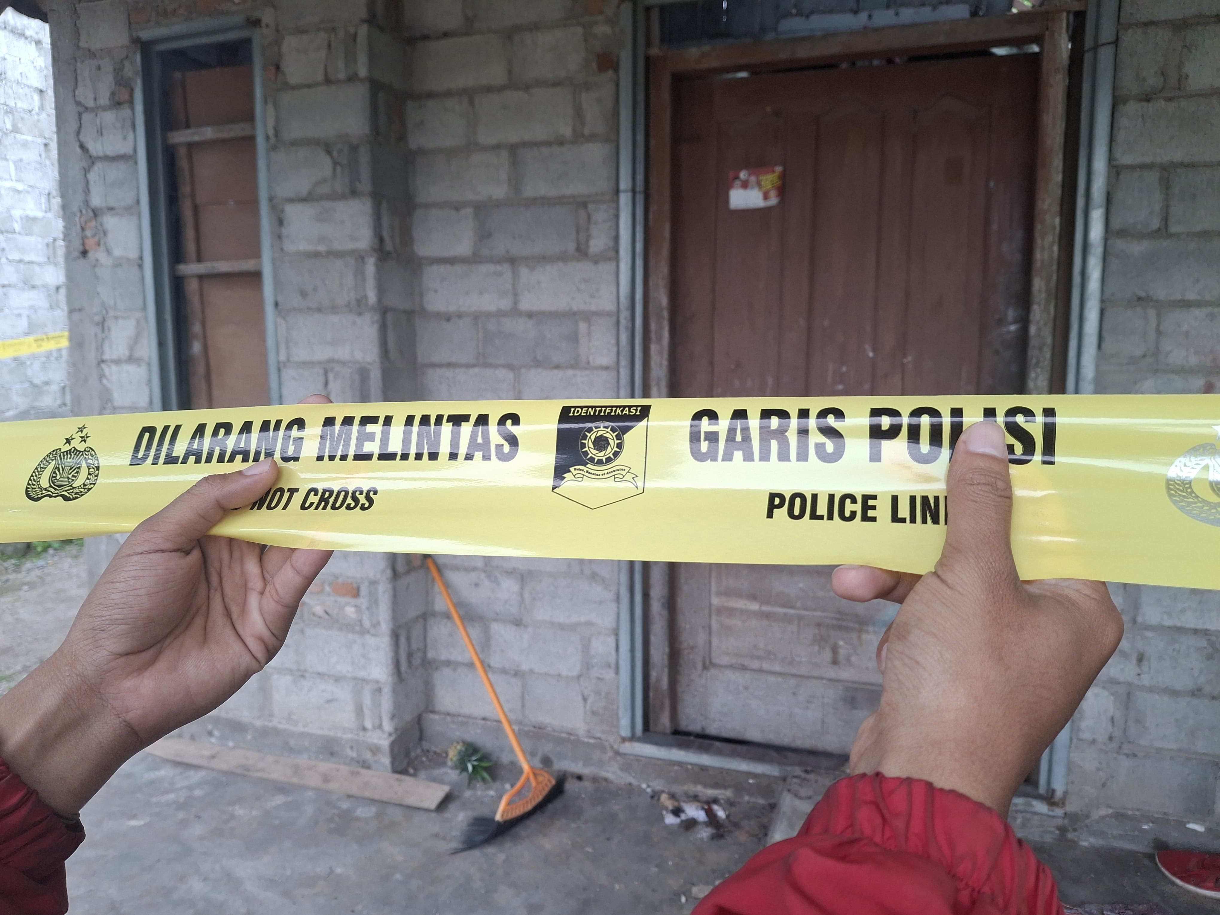 Petugas memasang garis polisi di TKP.
